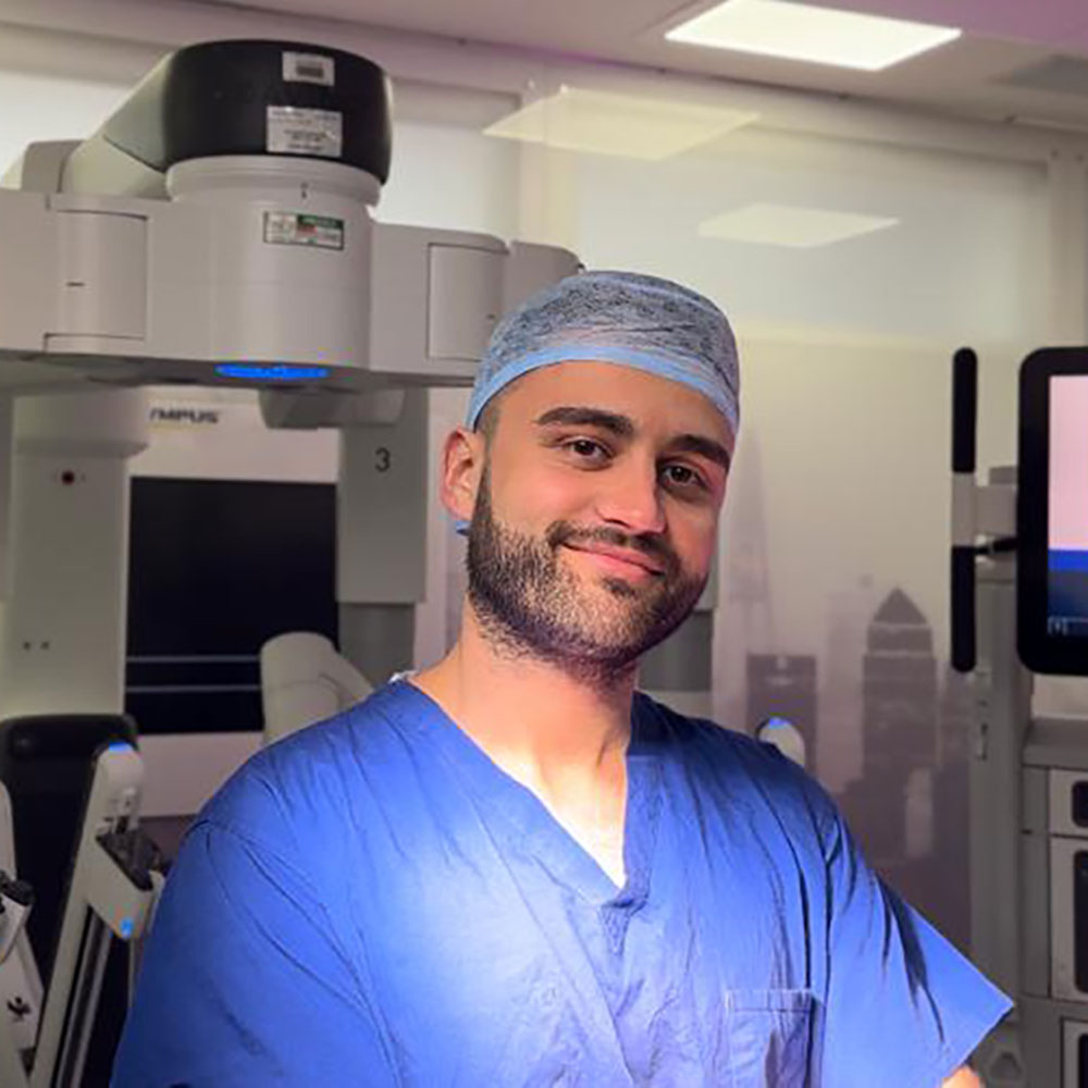 A surgical assistant beside a robotic surgical system.